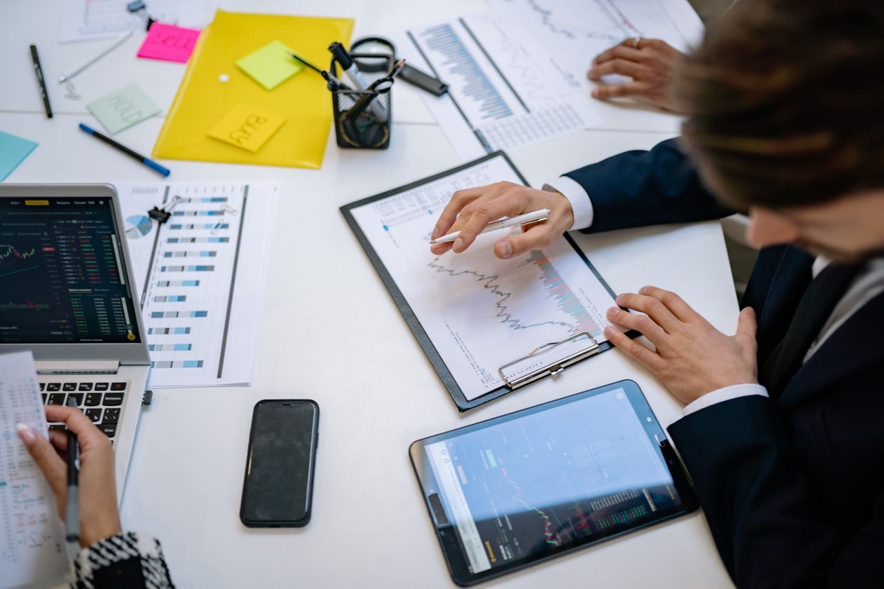 Équipe examinant des graphiques financiers et des données numériques sur des tablettes dans un environnement de bureau.